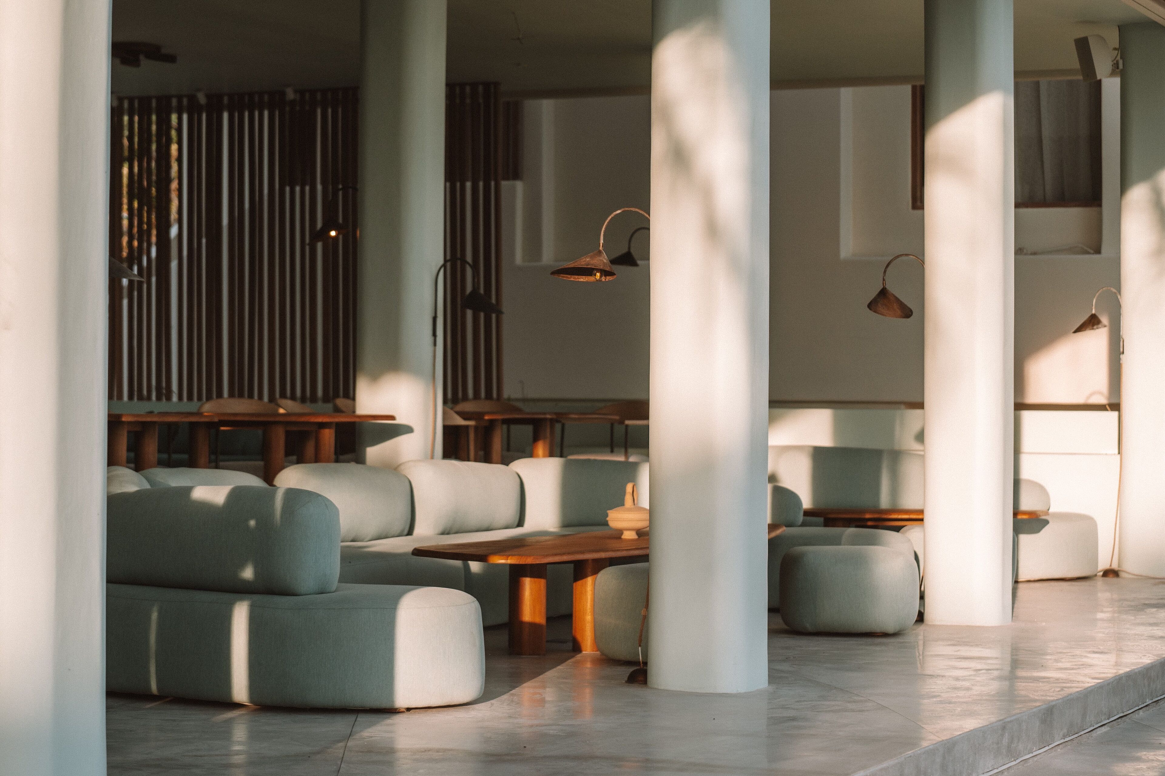 Un interior moderno con un sofá modular, una mesa de madera e iluminación colgante.