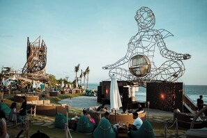 A beachside lounge area with outdoor seating and a large metal sculpture.
