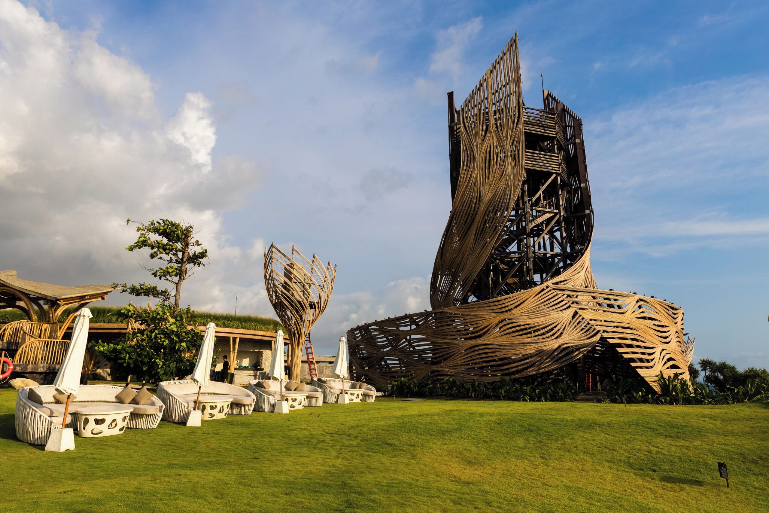 A modern architectural structure with a unique design, surrounded by outdoor seating areas and greenery.