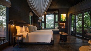 A bedroom with a large bed, a hanging light fixture, and a view of greenery outside. - Oshom Bali at Nuanu Creative City (Tabanan)
