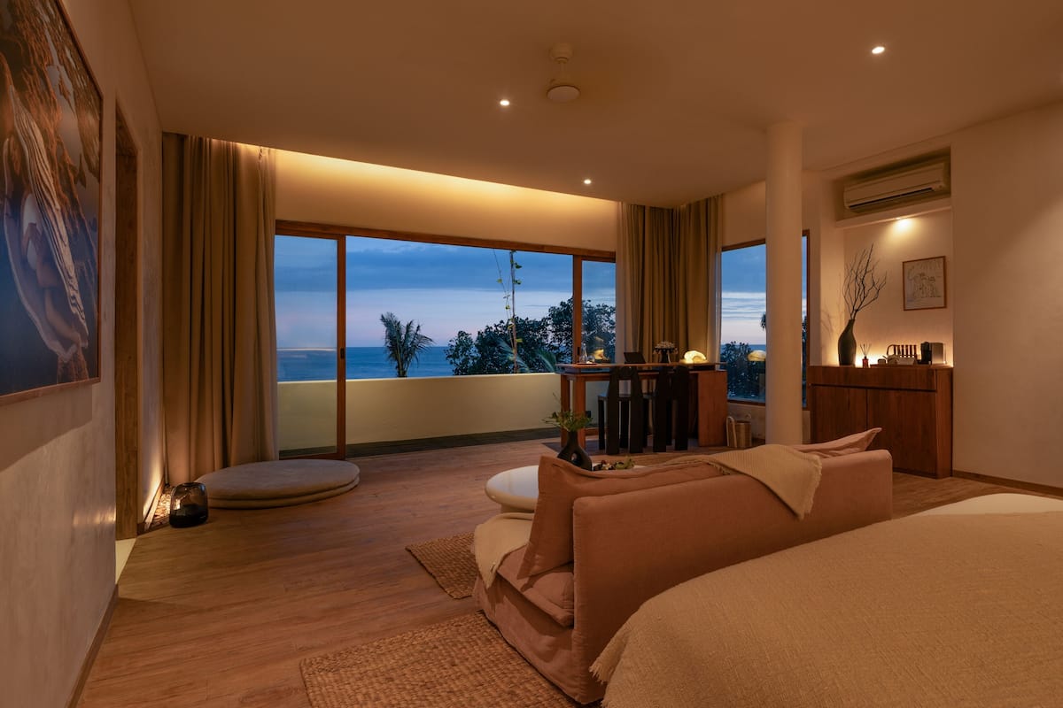 Une chambre moderne dotée d’une grande fenêtre, d’un balcon et offrant une vue sur l’océan.
