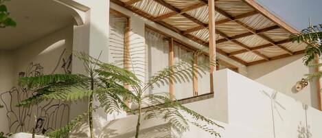 A modern building with a covered outdoor area, columns, and greenery.