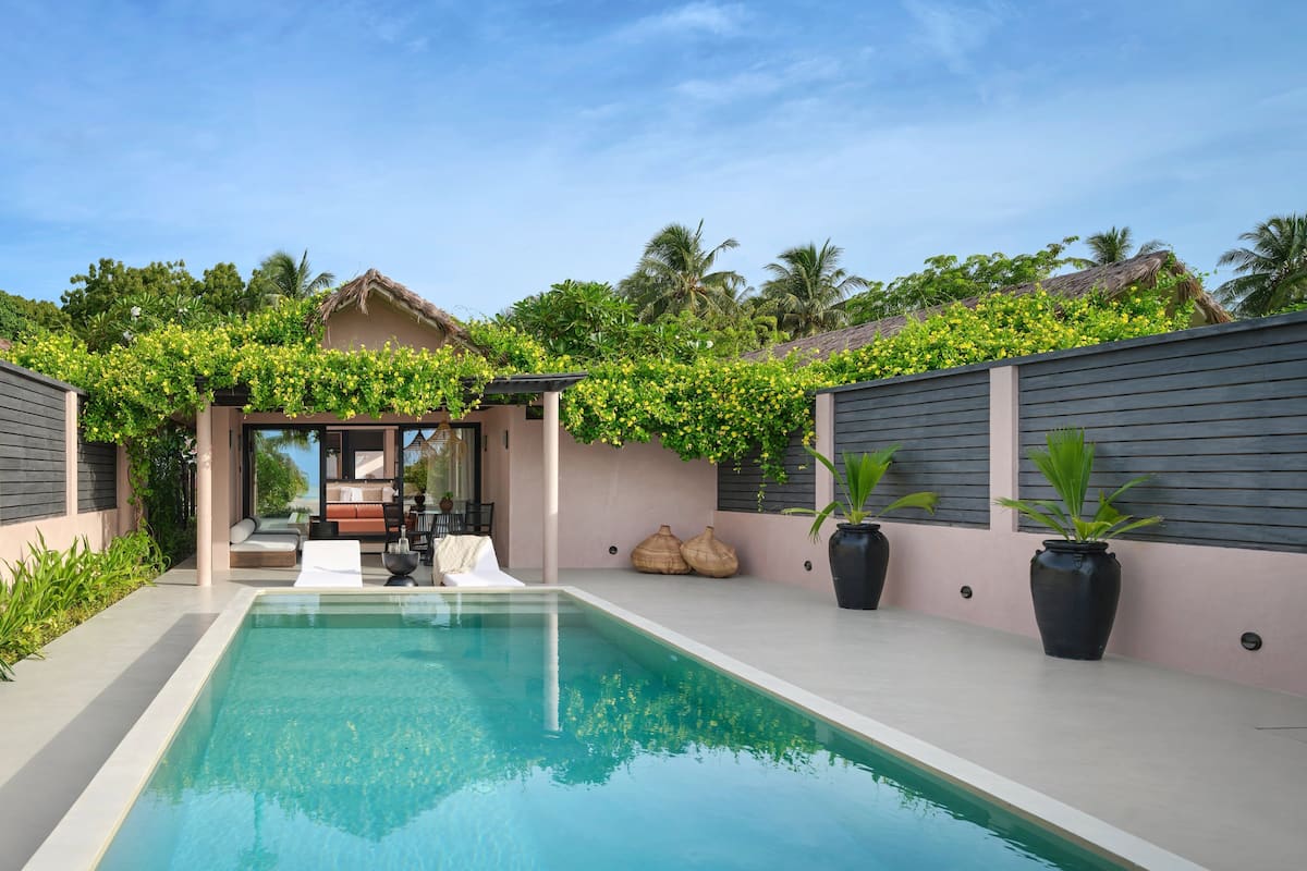 A modern pool area with a clear pool, lounge chairs, and a covered seating area.