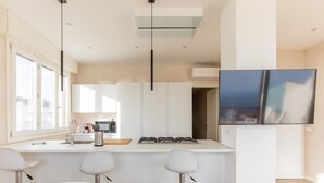 A modern kitchen with a central island, bar stools, and pendant lighting. - Luxurious and modern penthouse facing the sea with private solarium on the seafront of Lido di Camaiore with private parking space. The flat is on two levels.The flat opens with the bright living room where there is a comfortable doublebed sofa, dining a (Lido di Camaiore)