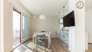 A modern kitchen with a dining area, a TV mounted on the wall, and a sliding glass door leading to an outdoor area. - Luxurious and modern penthouse facing the sea with private solarium on the seafront of Lido di Camaiore with private parking space. The flat is on two levels.The flat opens with the bright living room where there is a comfortable doublebed sofa, dining a (Lido di Camaiore)