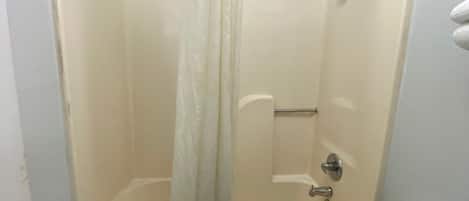 Un baño estándar con bañera, cortina de ducha, toallero y retrete.