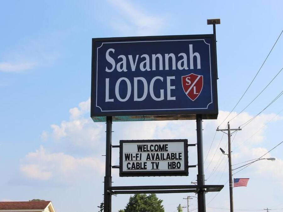 A sign for Savannah Lodge with amenities including Wi-Fi, cable TV, and HBO.