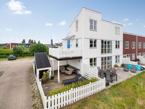 Un bâtiment moderne à deux étages, doté d’un espace extérieur aménagé et couvert, ainsi que d’une piscine.