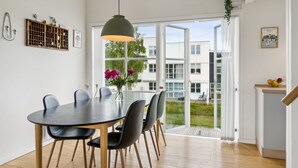 A modern dining area with a round table, chairs, and a hanging light fixture.