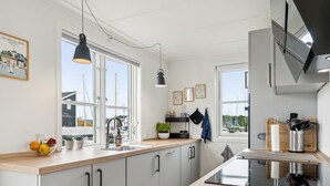 A modern kitchen with large windows, a wooden countertop, and a black stove.