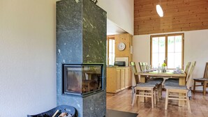 Moderni keittiö, jossa on kivinen takka, puinen ruokapöytä ja tuolit.