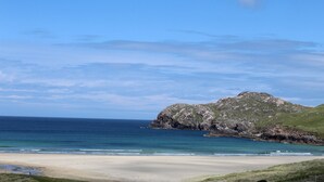Une plage avec un promontoire rocheux et un ciel bleu dégagé.