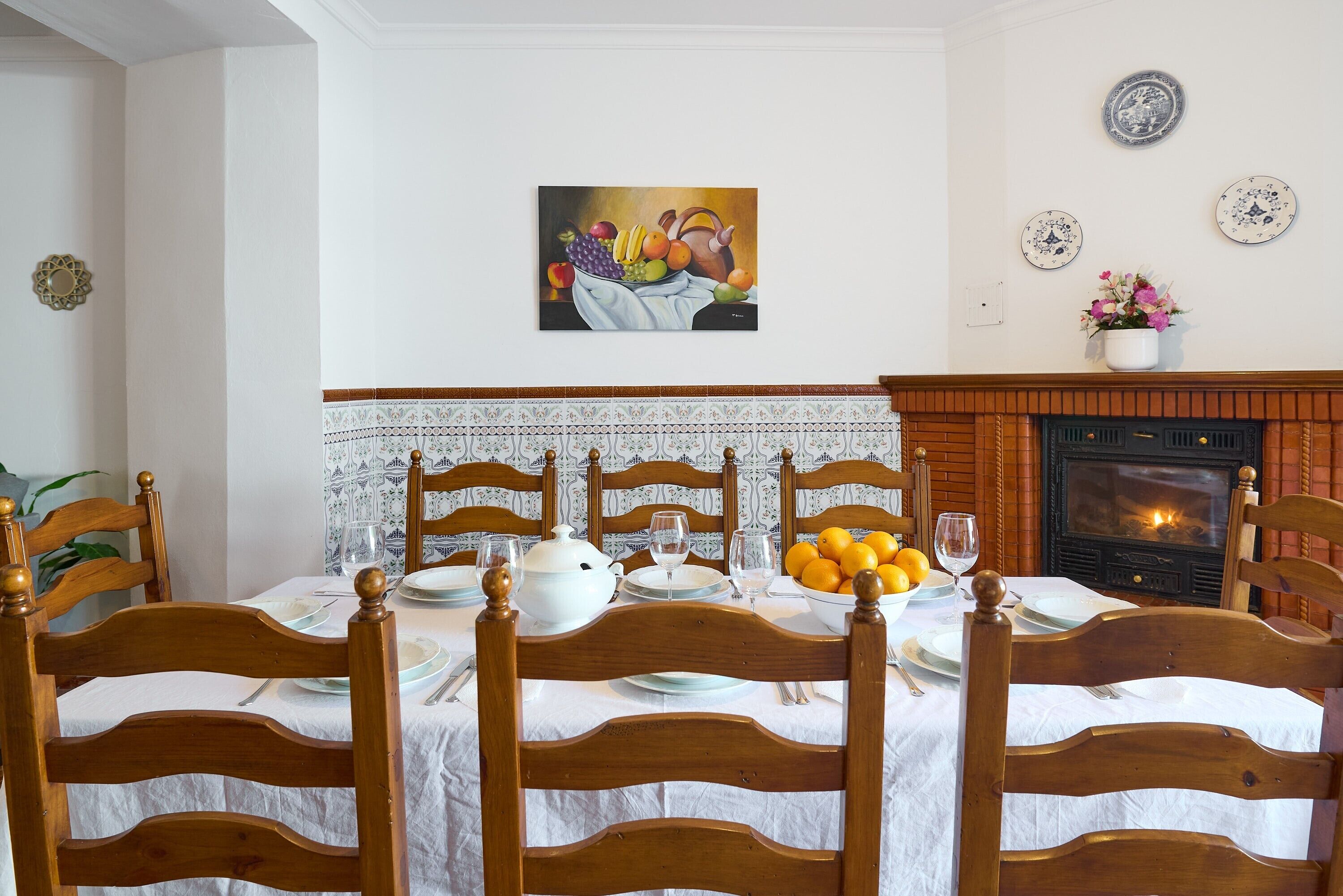 Ein Esszimmer mit Kamin, einem gedeckten Tisch für vier Personen und einem Gemälde darüber.