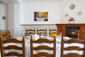 Een eetkamer met een open haard, een tafel gedekt voor vier personen, en een schilderij erboven.