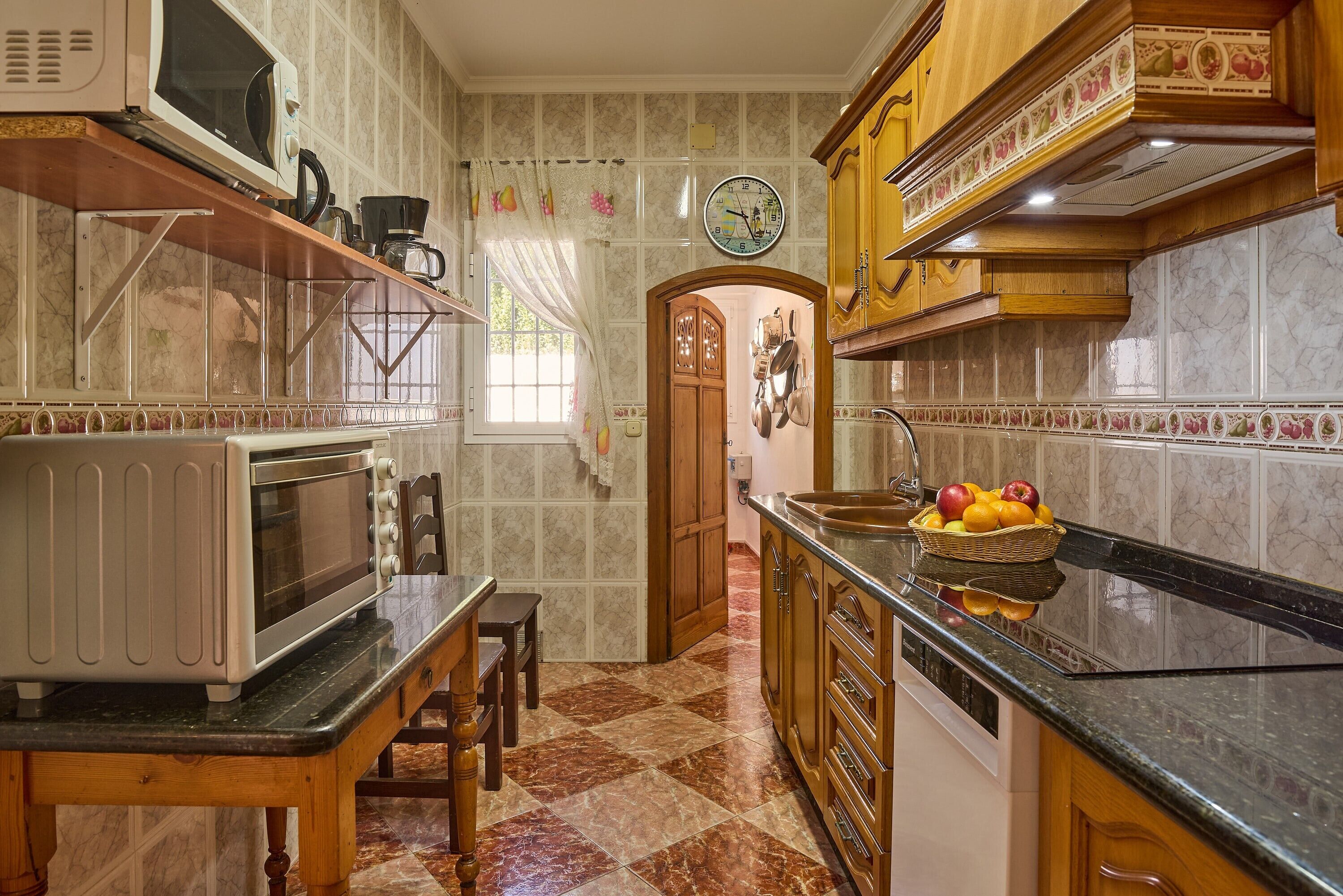 A kitchen with a microwave, toaster, and a fruit bowl on the counter.