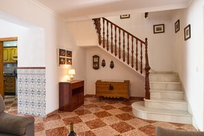 A staircase with wooden balusters, a wooden chest of drawers, a patterned curtain, and a tiled floor. - Vacation Home "Casa Ángeles" with Private Pool, 2 Private Terraces & Wi-Fi (Cuevas Bajas)
