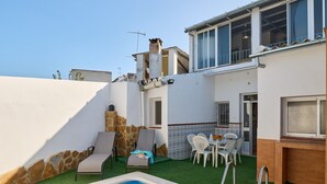 Area piscina con una poltrona da relax, un tavolo da pranzo con sedie e una zona cucina.