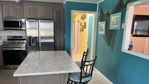 A kitchen with stainless steel appliances, a marble countertop, and teal walls. - Manatee Cove on the waterway with 5 acres. Pet Friendly. 5 minutes to the beach! (Port St. Joe)