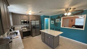 A kitchen with stainless steel appliances, a granite countertop, and teal walls. - Manatee Cove on the waterway with 5 acres. Pet Friendly. 5 minutes to the beach! (Port St. Joe)