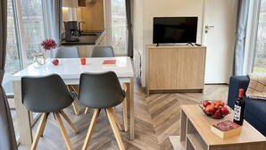Una sala de estar moderna con televisor, una mesa de comedor y una zona de cocina.