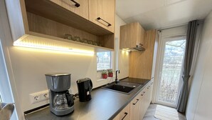 Una cocina moderna con cafetera integrada, un fregadero y armarios de madera.