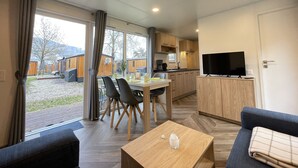 Interior moderno de um veículo recreativo, com área de refeições, cozinha e sala de estar.