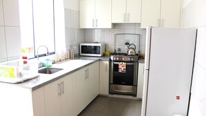 Une cuisine avec des meubles blancs, un four à micro-ondes, une cuisinière et un réfrigérateur.