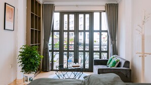 A room with a large window, a sofa, a small table, and a potted plant.