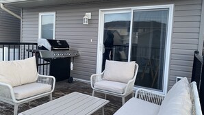 A patio with outdoor furniture, a grill, and a sliding glass door.