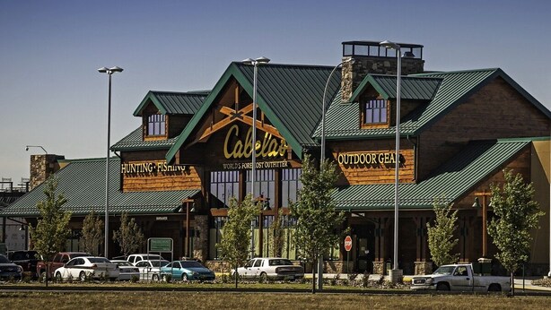 A building with a green roof and wooden facade, labeled "Cabell's" and "Hunting & Fishing Outfitters."