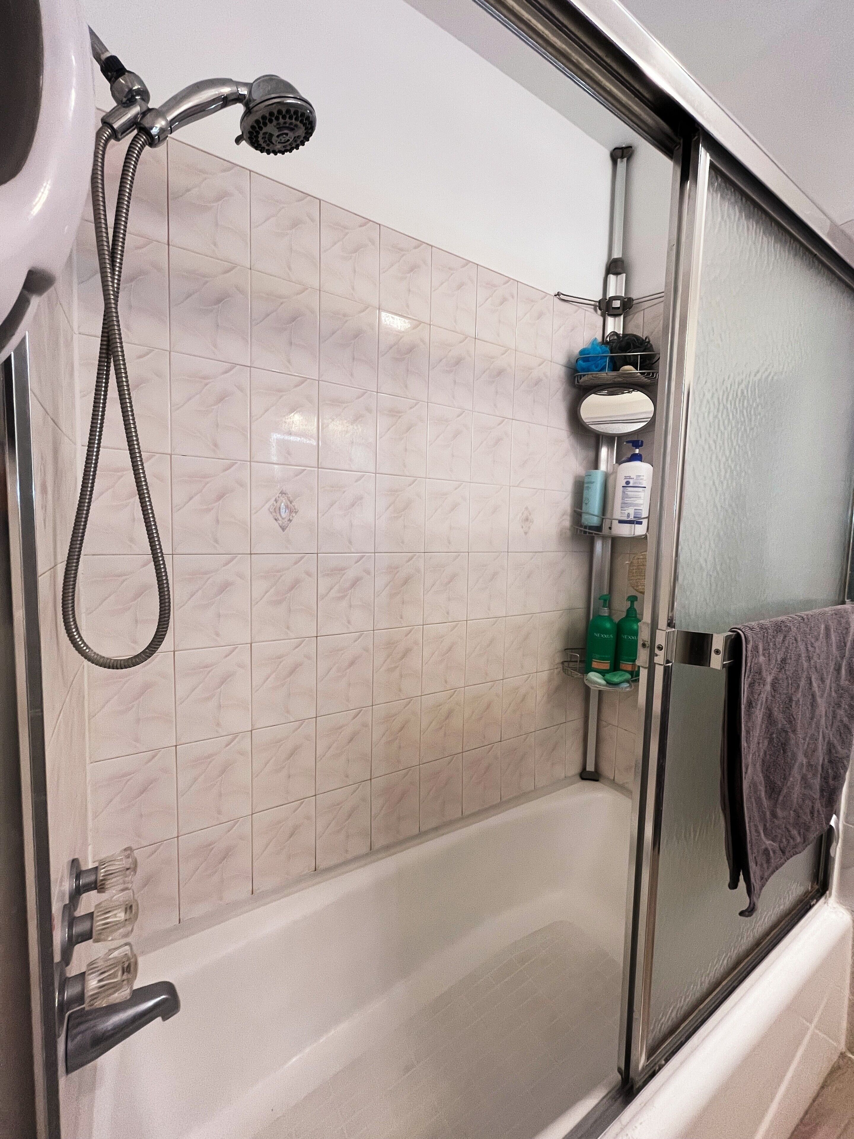 A bathroom with a shower, a glass-enclosed tub, and a towel rack with a towel.