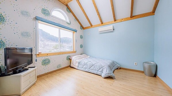 Un dormitorio con cama, televisión, ventana y techo de madera.