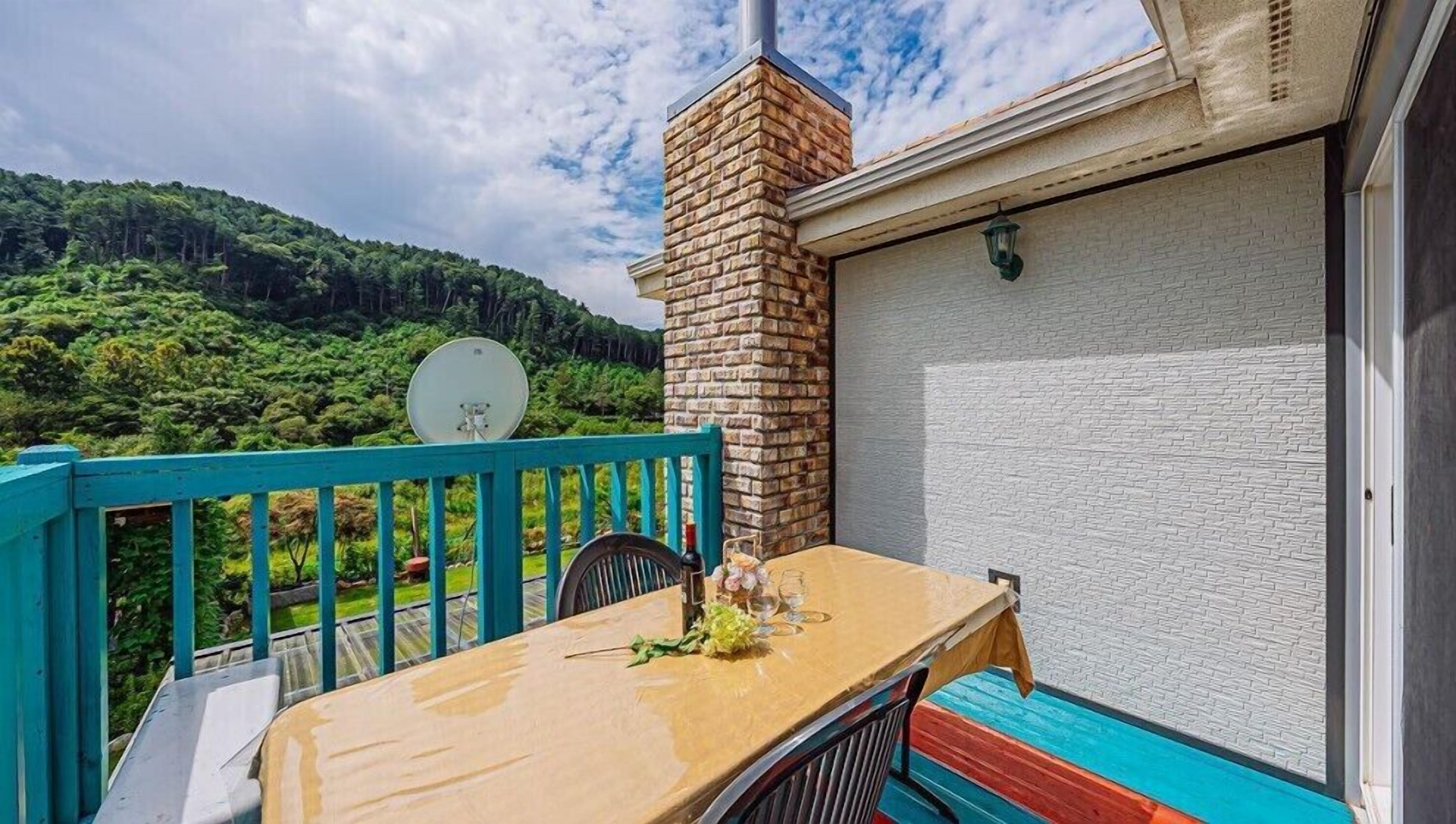 A balcony with a table, chairs, and a brick chimney.