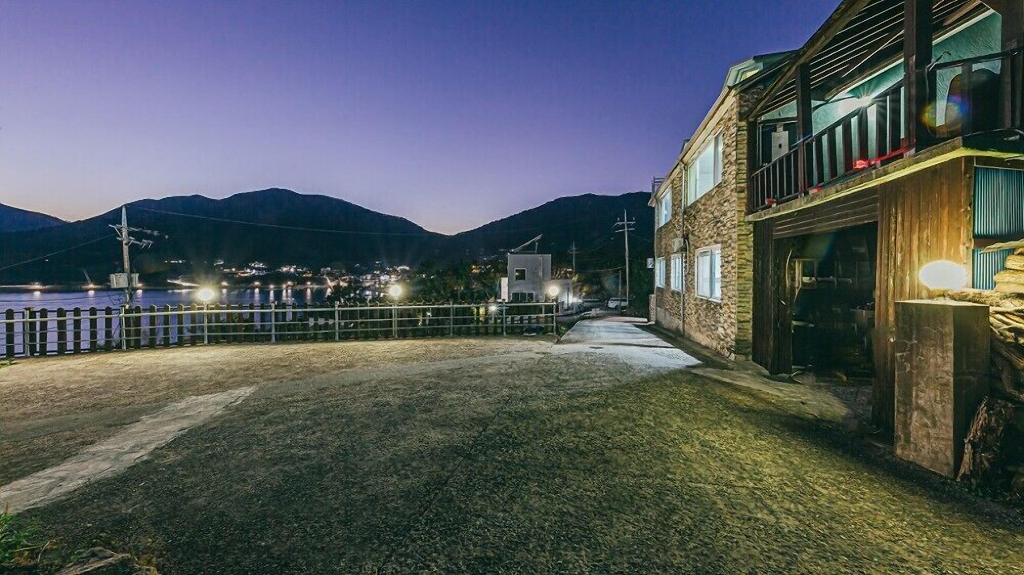 A waterfront property with a stone building, a wooden deck, and a view of the water and mountains in the background.