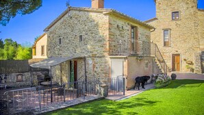 Un bâtiment en pierre doté d’un balcon, d’un petit espace extérieur aménagé pour s’asseoir et d’un chien.