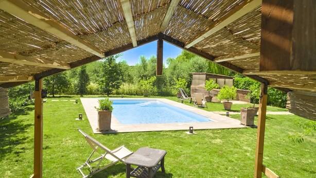Un espace extérieur abrité comprenant une piscine, des chaises longues et des plantes en pot.