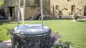 Une fontaine en pierre se trouve dans une cour, avec un bâtiment en pierre en arrière-plan.