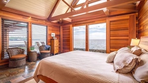 Ein Schlafzimmer mit einem großen Bett, Holzwänden und Blick auf das Meer.