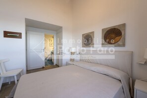 A bedroom with a bed, a bedside table, a chair, and artwork on the wall.