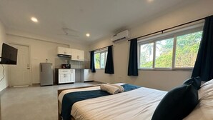 A bedroom with a bed, a small kitchenette, and a window with curtains. - Serenova by Dia Hotels (Calangute)