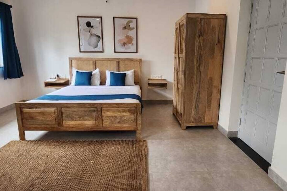 Une chambre avec un lit en bois, une grande armoire et un téléviseur fixé au mur.
