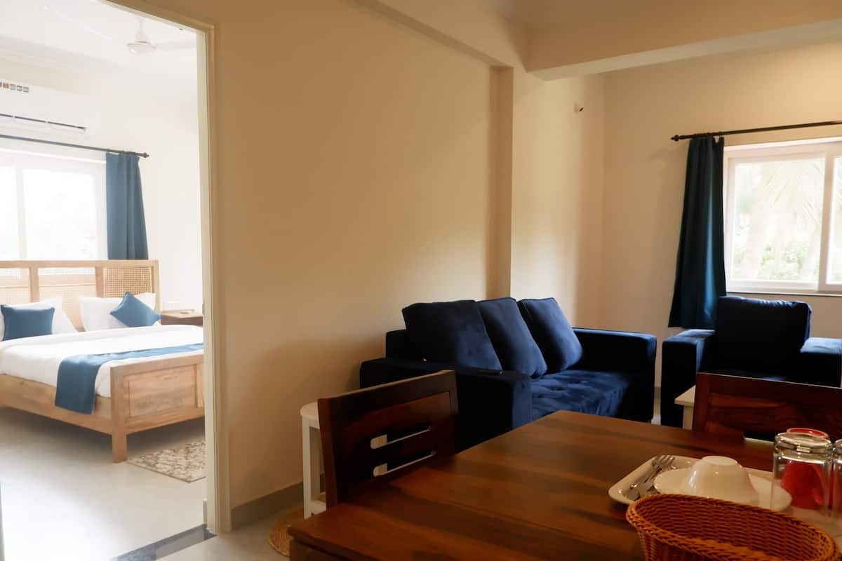 Une chambre d’hôtel avec un lit, une table en bois sur laquelle se trouve un panier, et un canapé de couleur sombre.