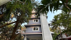 A multi-story building with a central staircase, surrounded by lush greenery. - Serenova by Dia Hotels (Calangute)