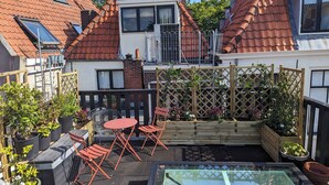 A rooftop garden with a glass table, red chairs, and potted plants. - Het Pakhuis Haarlem - Historic House (Haarlem)