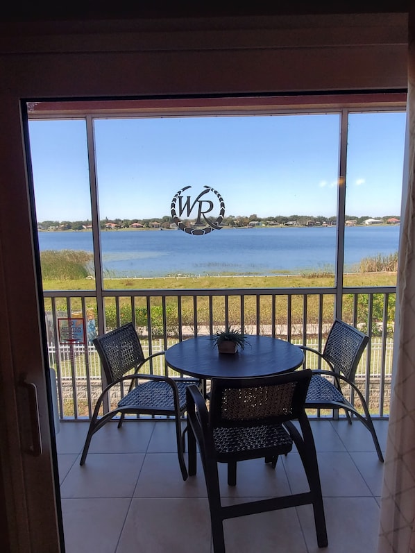 Balcón con mesa y sillas con vista a un lago.
