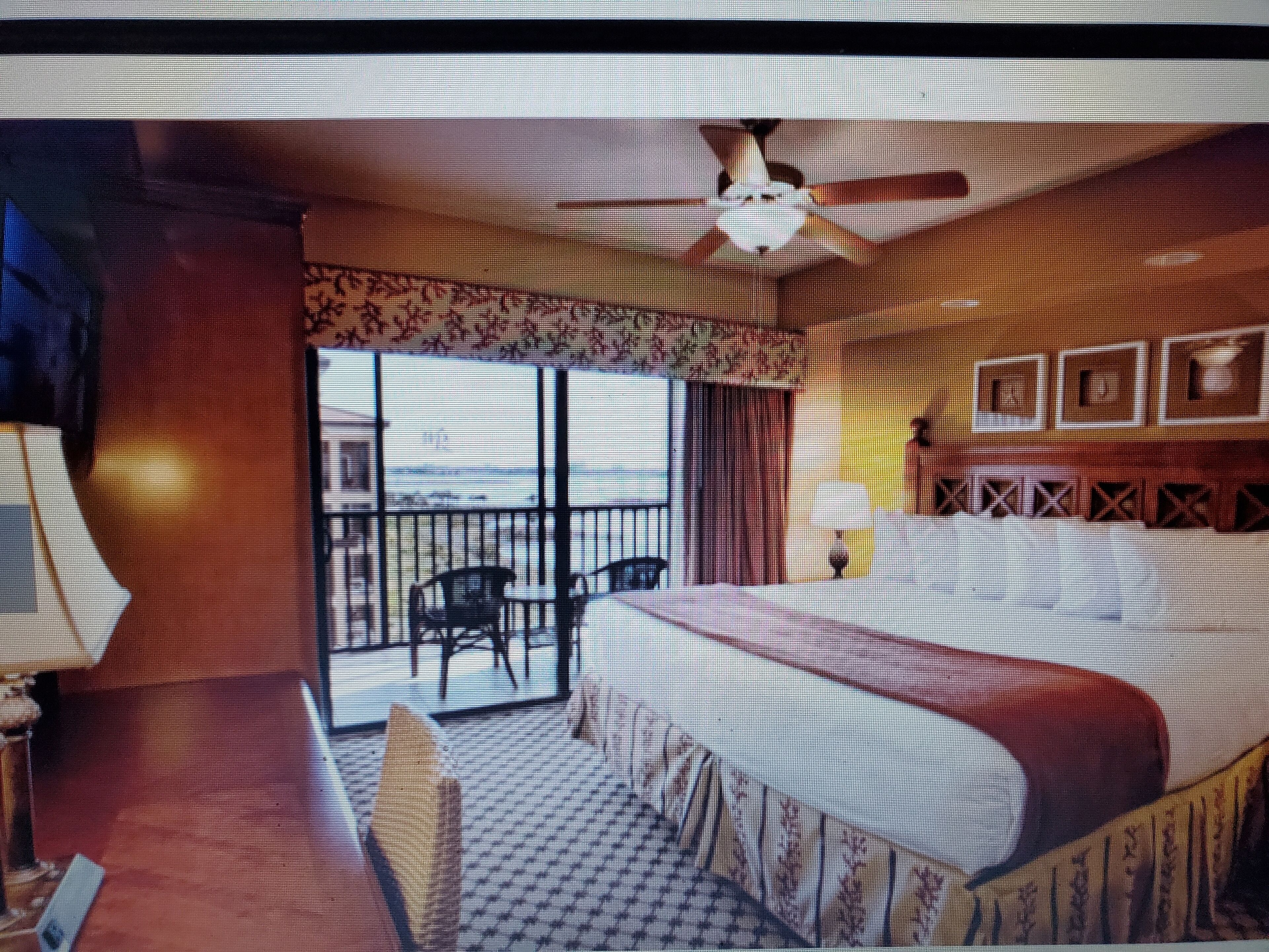 A hotel room with a bed, a chair, a table, and a balcony with a view.