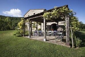 A stone building with a covered patio area, outdoor seating, and a view of the surrounding landscape.