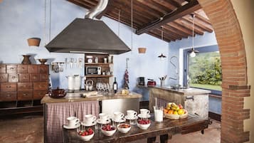 Una cucina rustica con parete in mattoni, pensili in legno e una grande isola con prodotti per la colazione.