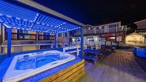 A hot tub area with a wooden deck and a covered seating area with blue lighting. - Fun and Happy pension (Jeongseon)
