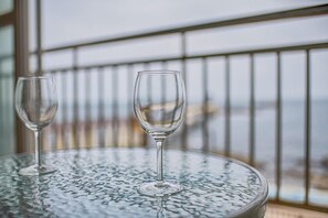 Two empty wine glasses on a textured glass table with a view of a railing and a distant landscape. - Bolisdol Pension (Pohang)